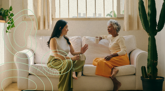 Adult daughter and her mother sitting on a couch having a heartfelt conversation using Actually Curious cards, showing meaningful Mother’s Day connection.